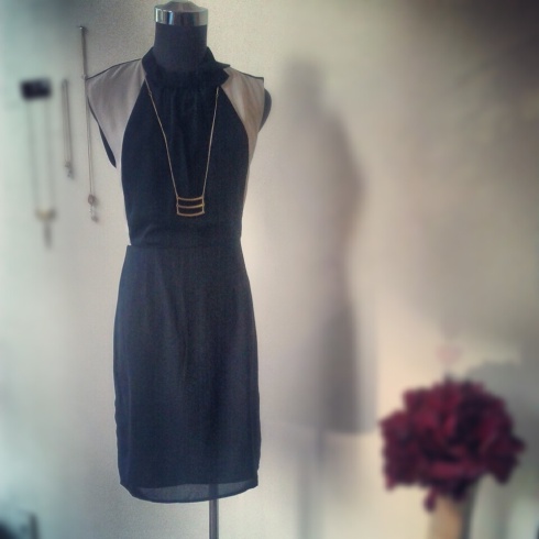 Black and ivory bow-collar dress with tiered gold-bowed necklace by KURVE