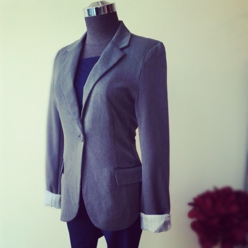 Grey blazer with striped cuff detail, as paired with denim legging and navy knit tee underneath.
